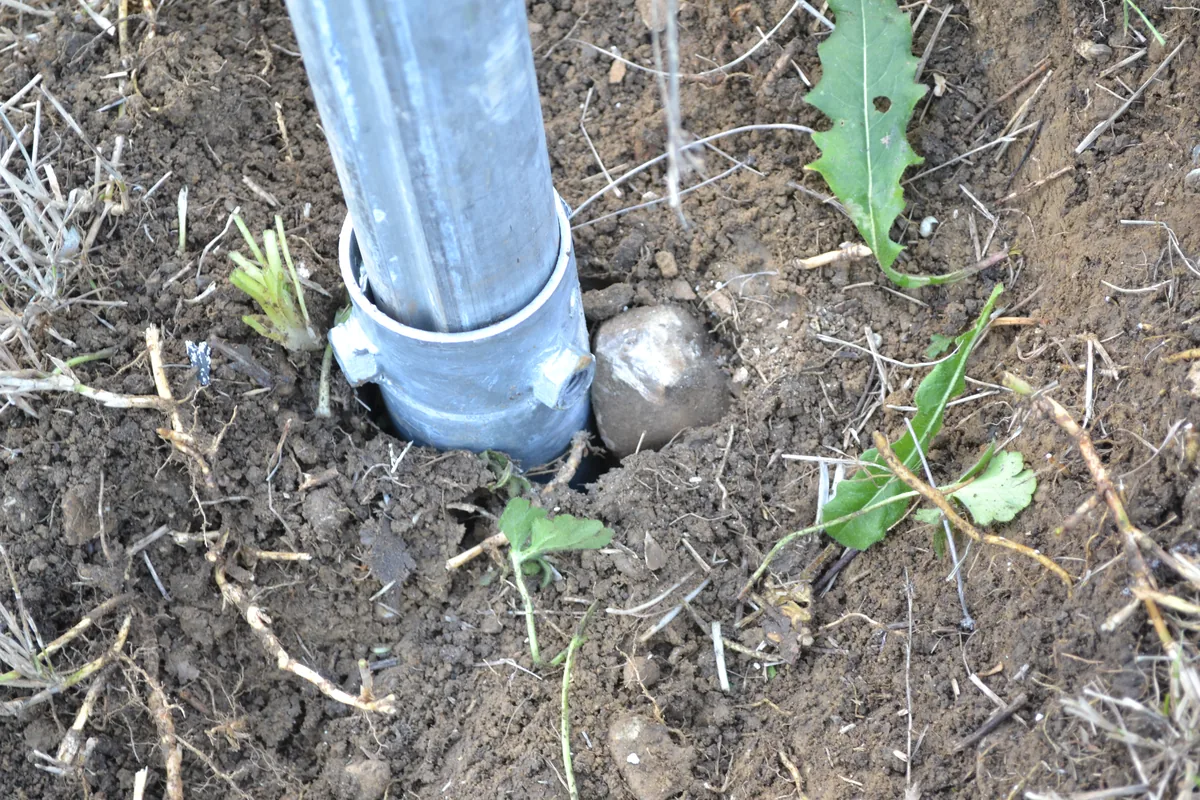 Piede del palo di un cartello stradale infilato nella parte alta di un T-Block senza testa, a filo del terreno.