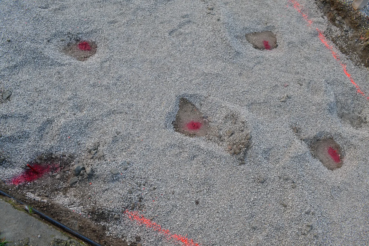 Punti di posa segnati con vernice spray rossa sulla ghiaia, pronti per i T-Block.
