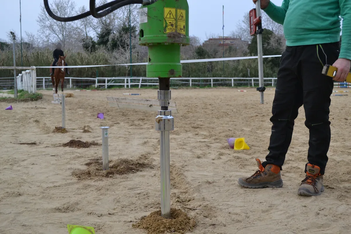 La testa rotativa verde che porta il T-Block quasi a fine corsa, con l'operatore a terra accanto.