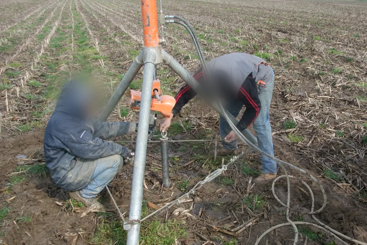 Due operatori collegano il tirante del martinetto alla testa del T-Block, sotto il treppiede.
