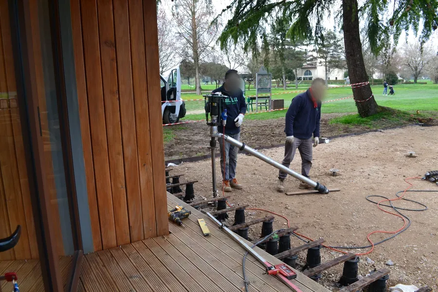 Pedana in legno montata sui piedini avvitati alle teste delle viti, mentre la squadra posa le fondazioni a vite T-Block per l'estensione della pedana.