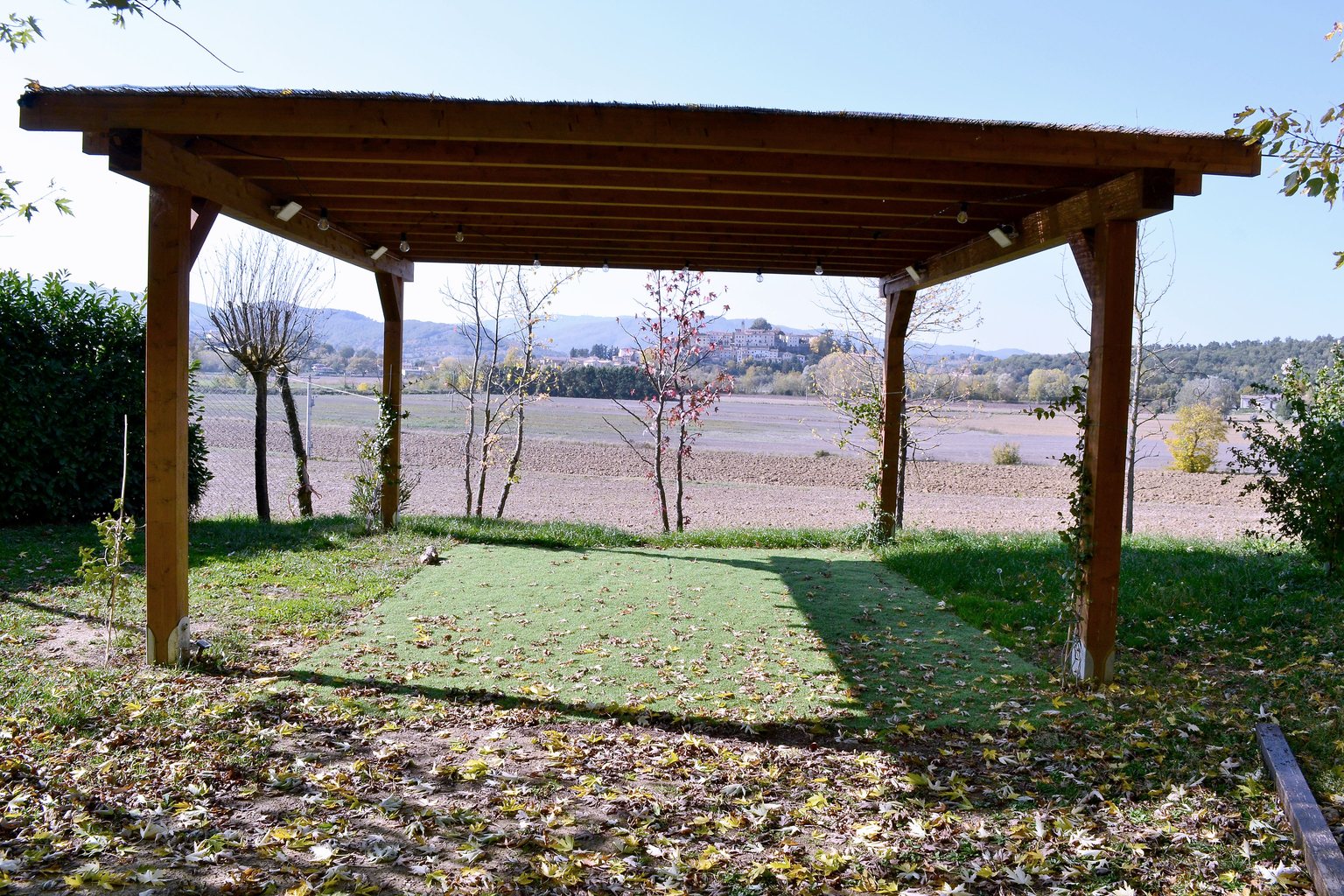 Pergola en bois sur la pelouse d’un restaurant de campagne, avec les poteaux ancrés au sol par des vis de fondation T-Block.