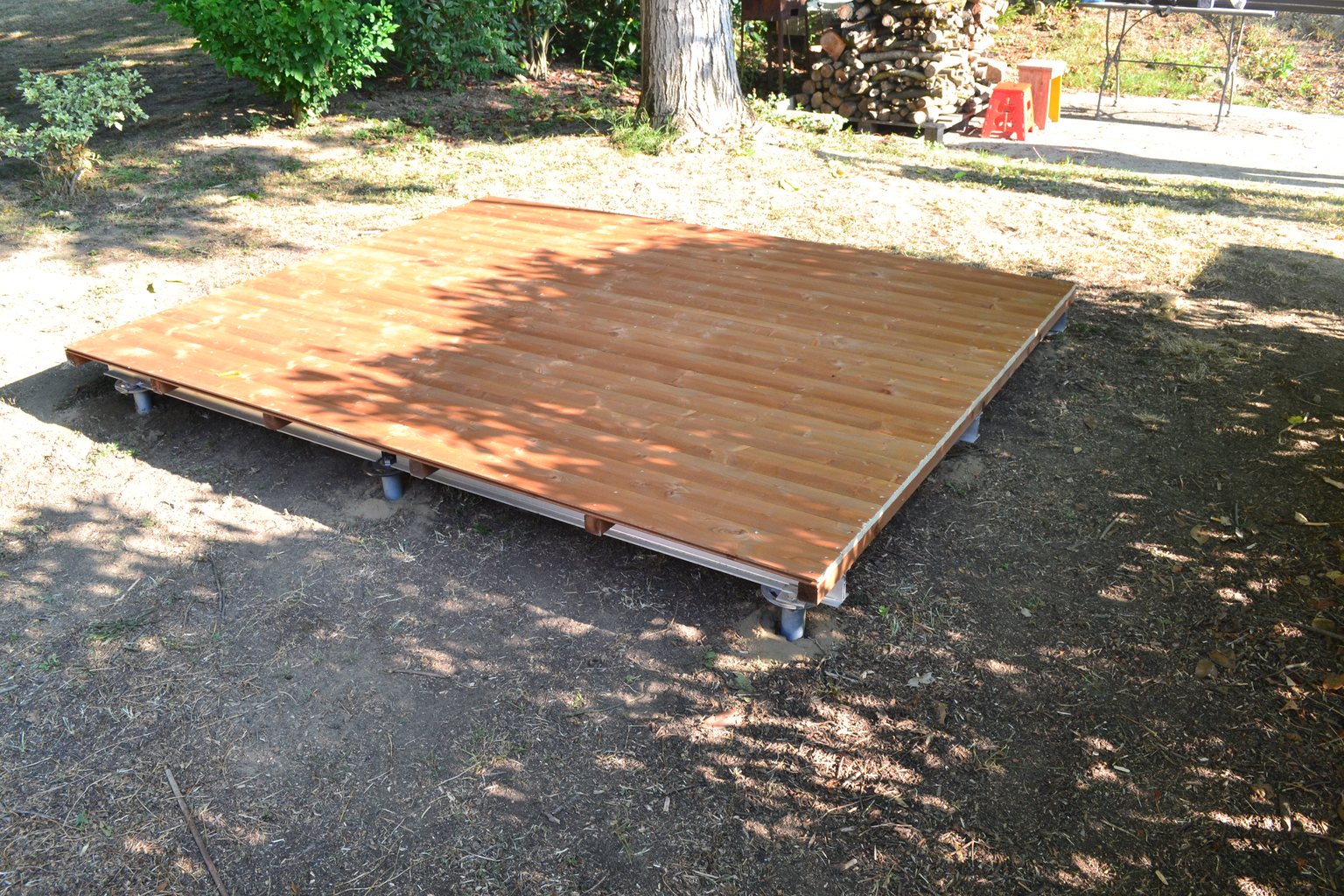 Pavimento in legno di una casetta da giardino montato sul telaio in alluminio, ancorato a terra con fondazioni a vite T-Block.