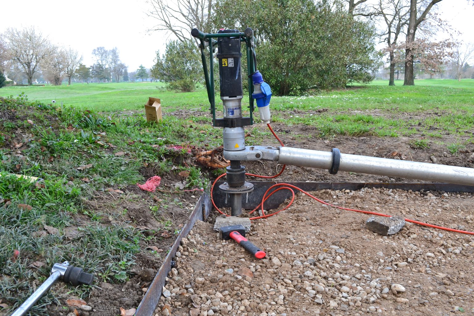 Avvitatore elettrico TBDriver montato sulla bussola di un T-Block, con la barra di contrasto in alluminio appoggiata a terra ai bordi di un campo da golf.