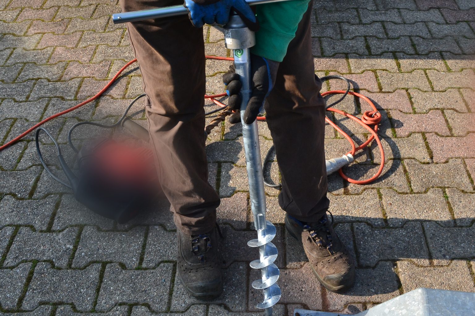 Operatore che avvita a mano un T-Block con il manico a T, in piedi sulla pavimentazione in autobloccanti di un piazzale.