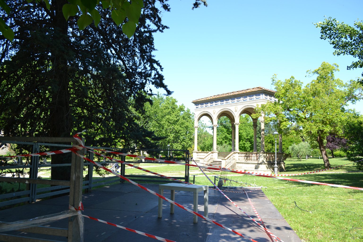 Allestimento di un palco nel prato del Giardino dell'Orticoltura a Firenze: le pedane modulari poggiano su fondazioni a vite T-Block, con la loggia sullo sfondo.