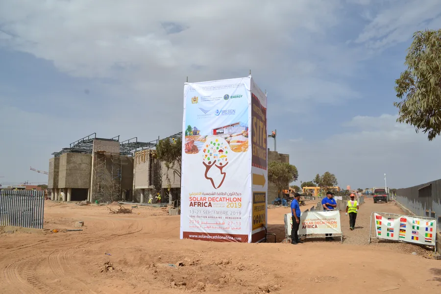 Ingresso del Solar Decathlon Africa 2019 a Benguerir: il cartellone con le date, 13-27 settembre 2019, e i prototipi sullo sfondo.