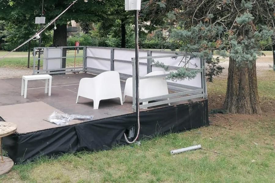 Palco con le sedute bianche sotto gli alberi dei Giardini dell'Orticoltura a Firenze, appoggiato su fondazioni a vite T-Block nel prato.