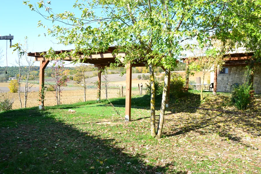 Pergola in legno in un giardino in collina, con i montanti ancorati al terreno da fondazioni a vite T-Block.