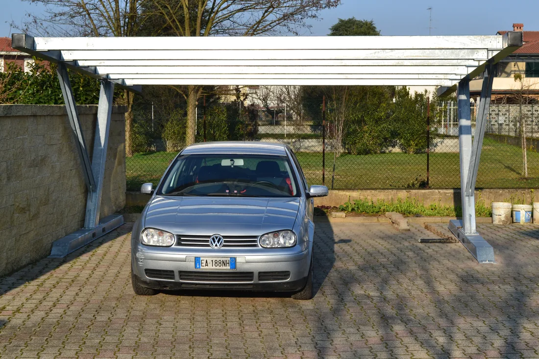 Carport su un cortile pavimentato, con i montanti ancorati da fondazioni a vite T-Block senza plinti.