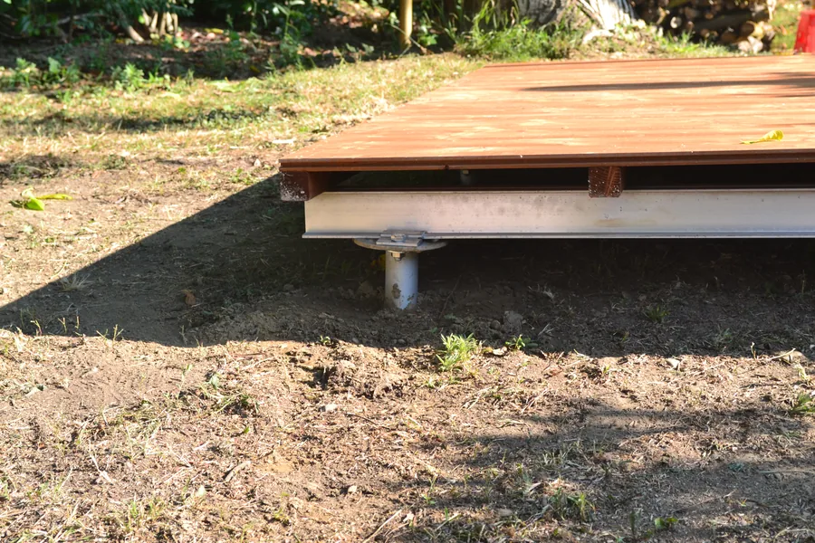 Vista laterale di una pavimentazione in legno su telaio metallico ancorata al terreno con fondazioni a vite T-Block.