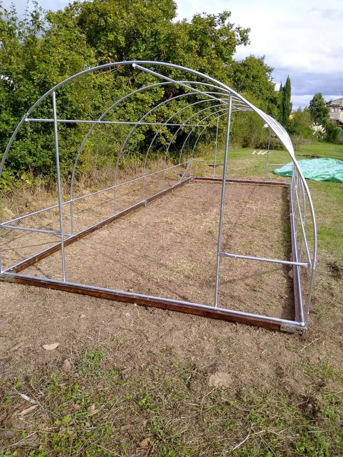 Archi in tubo zincato di una serra a tunnel familiare montati sul telaio di base, appoggiato su fondazioni a vite T-Block.