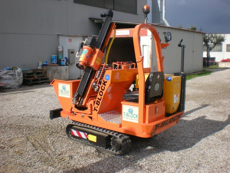 Macchina cingolata a colonna arancione con marchio T-Block e testa di avvitamento idraulica, sviluppata per l'installazione delle fondazioni a vite.