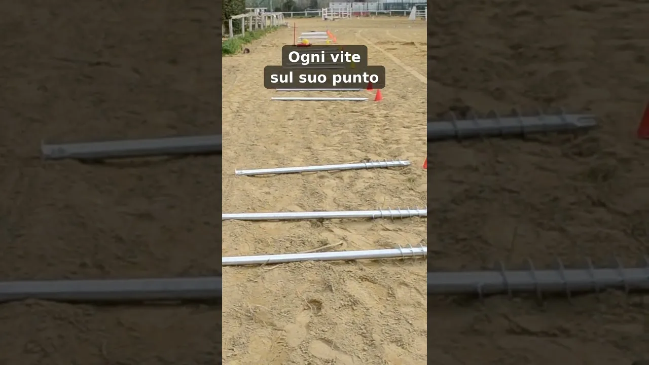 Nel campo in sabbia di un maneggio, le fondazioni a vite T-Block stese in fila sui punti segnati da coni arancioni.