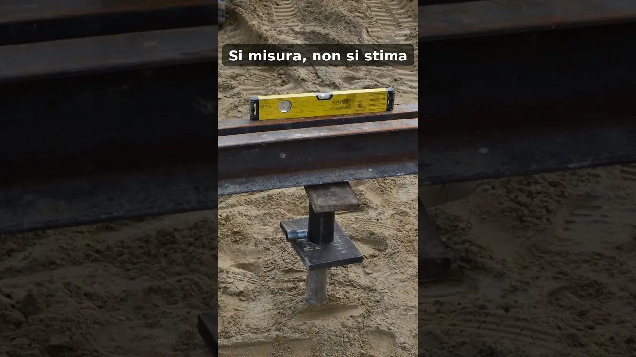 Un T-Block avvitato nella sabbia sotto la trave di riferimento, con una livella gialla appoggiata sopra.