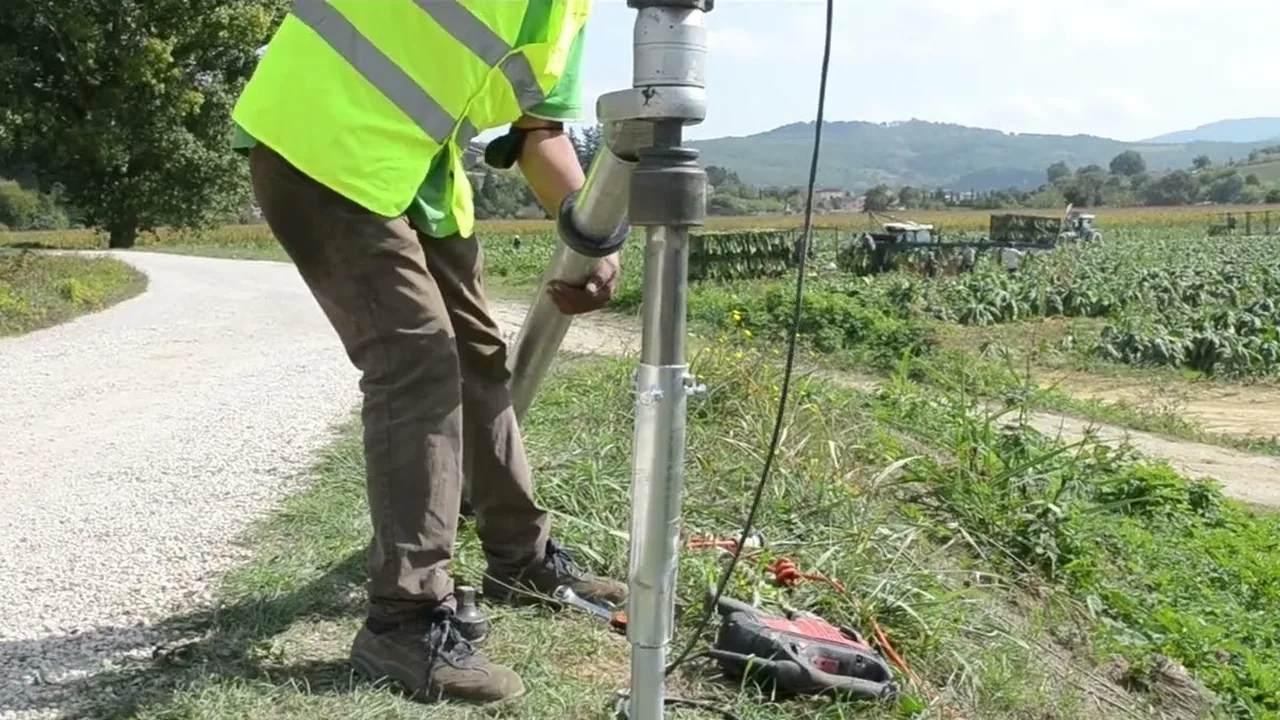Operatore che avvita un T-Block senza testa a bordo strada con l'avvitatore, fra i campi.